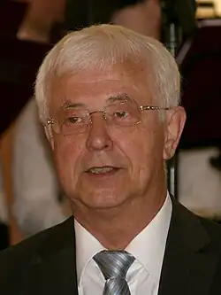 Image of an elderly man wearing a suit and a tie.