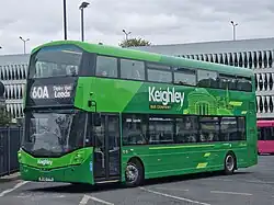 Green angular double-decker bus departing a bus station