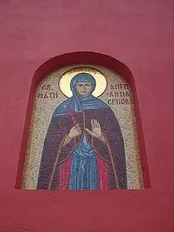 Outer wall of Krušedol Monastery, containing a mosaic of Saint Angelina in monastic vestments and holding a red Byzantine cross