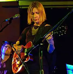 blonde woman playing guitar