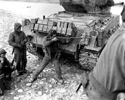 Black-and-white photograph of a U.S. soldier aiming an M1918A2 Browning Automatic Rifle from behind an M4A3(76)W HVSS Sherman tank, Korean War, 1951.