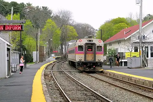 A passenger train leaving a railway station in a village center