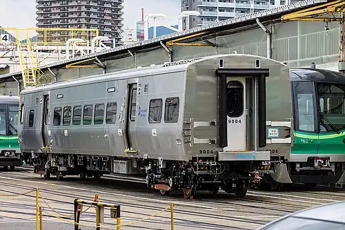 Car no. 9004 at Kawasaki Heavy Industries' Hyogo plant in 2017, in front of a Tokyo Metro 16000 series