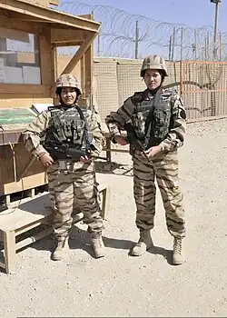 Two female Malaysian Army medical personnel, a paramedic and a dental nurse, standing guard in 2011 while serving in Afghanistan under ISAF. They are wearing the desert version of the tiger-stripe camouflage combat uniform. Malaysian Army medical staff typically rotated between medical duties and guard duties to protect their compounds from enemy threats. This camouflage pattern remained in use until 2013.