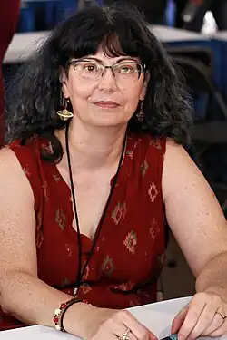 Wells, with sleeveless dress, sits at a table