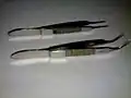 Upper one: Suture tying forceps; Lower one: Iris forceps; For comparison
