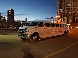 Photo of limousine on street in front of dusk cityscape