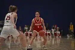 A player with a basketball, guarded by a defender