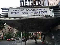 Side view of the Metro Theater, a three-story movie theater. The main entrance is to the right, and a large rectangular marquee is located above the entrance.