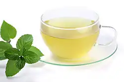 Glass of mint tea beside mint leaves