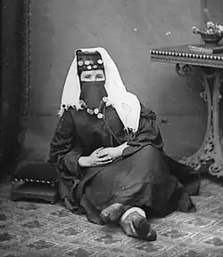 Margaret Jones poses for a portrait. She is wearing a loose black outfit and a decorated head covering that shows only her eyes.