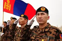 Mongolian soldiers salute while the Mongolian flag waves at the Transit Center at Manas, where they stayed for several days before moving forward to Afghanistan to support Operation Enduring Freedom.