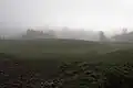 A low earth mound with ditch shrouded in mist