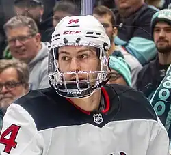 Ice hockey player in a white jersey and helmet wearing a clear visor