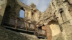 A ruined stone structure with a wooden walkway halfway up the wall.