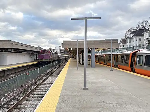 A passenger train and a metro train at a brutalist-style station