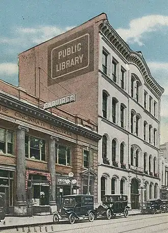 Colored photograph of the facade of the Old Main Library, with vintage cars in the foreground