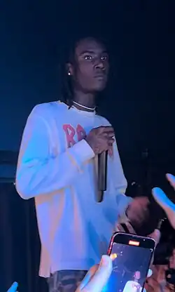 A man on stage performing in front of a crowd while holding a mic