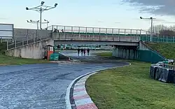 The bridge in the first sector of PF International Kart Circuit with four people walking beneath