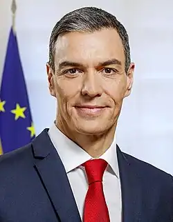 (Top image): Pedro Sánchez staring at the camera with a neutral expression, in a suit and a neck tie with the colors blue, black, & yellow arranged in a tartan like pattern. (Bottom image): Pedro Sánchez' signature