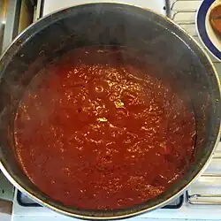 Dark red liquid in a pot, with a few bubbles breaking at the surface