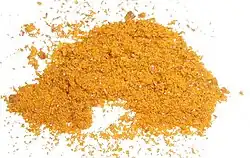 Photograph of yellow-orange ferrocene powder on a white background.