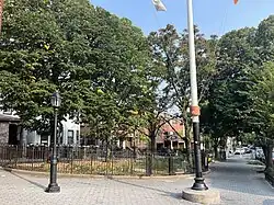 Small triangular park surrounded by a fence.