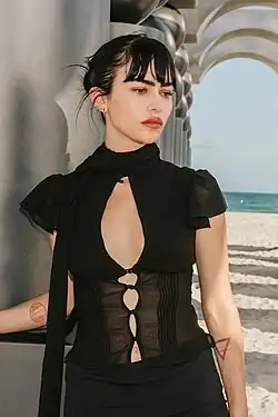 A dark haired white woman wearing a black dress