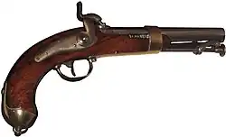 Side view of a 19th-century flintlock pistol with a curved wooden grip, metal trigger guard, exposed hammer, and a short metal barrel, shown against a white background.
