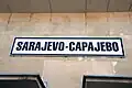 A sign at platform level, with the name in Bosnian/Croatian and Serbian.