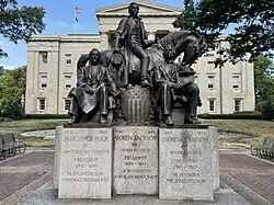 A color photograph of a metal monument depicting three men, one of whom on horseback