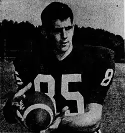 A football player stands, wearing the number 85 and holding a football