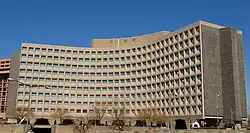 A portion of the Weaver Building's curved concrete facade as seen from a nearby street. The facade has windows set within the concrete.