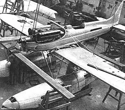 A single-engined floatplane is being built in a hangar, the engine covers are removed.