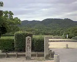 Modern stele in front of a park-like area.