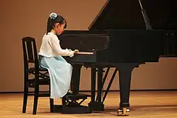 A girl plays the piano during a recital
