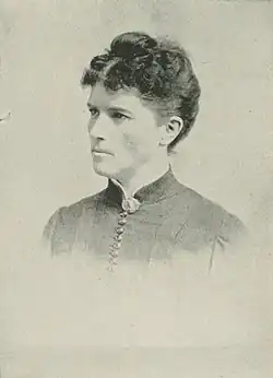 19th-century B&W portrait photo of a woman with her hair in an up-do, wearing a dark, fitted blouse.