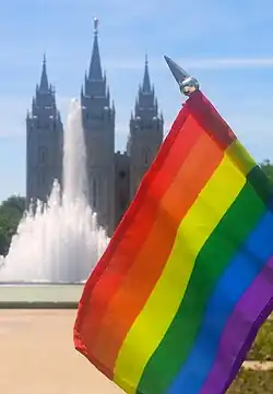 A gay flag with an LDS temple seen in the background