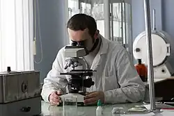 Student in a laboratory working with a microscope and scientific equipment during a microbiology session at the Faculty of Chemistry, Belarusian State University.
