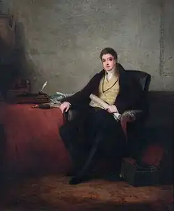 Freeling, seated in a lavish room in formal eighteenth-century dress, appears as a youngish man with short hair, holding a roll of papers and leaning on a desk with writing equipment