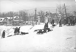 group of people, some on toboggans, on snowy white hillside