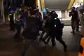Riot police and a Special Tactical Contingent officer leap from Lung Cheung Road to the pavement to subdue a person.