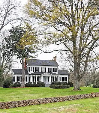 A white, two-story house with one-story wings