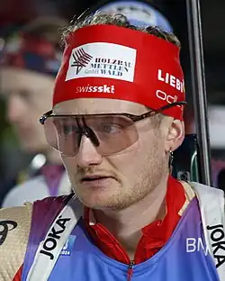 Sebastian Stalder wearing ski goggles and a red headband during a biathlon event.