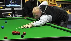 Photograph of Stewart Bingham leaning over a snooker table looking down his cue