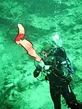 A diver preparing to inflate a delayed surface marker buoy