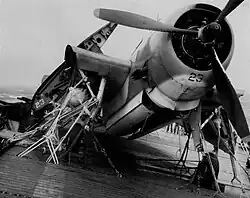 A front profile of a propellered aircraft. Numerous restraints have been placed onto it, tying it to the flight deck.