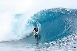 colour photograph of a surfer tube riding a large wave