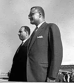 Two men standing in suits looking in the same direction
