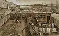 An extremely intricate drawing in exact perspective of a backyard seen from above. There is laundry hanging out to dry in the foreground and meadows with some buildings on the horizon in the background.